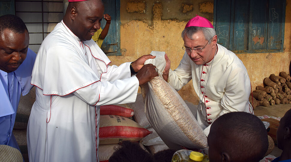 Erzbischof Kaigama und Erzbischof Schick übergeben Nahrungsmittel in einem Flüchtlingslager in Jos in dem Menschen Schutz vor dem Terror von Boko Haram suchen.